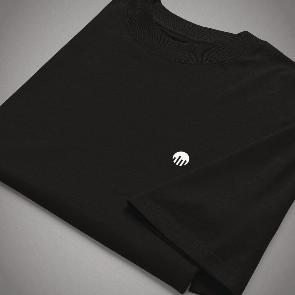 Nahaufnahme eines gefalteten schwarzen Oversized T-Shirts der Marke FORCE ZERO aus der Rogue Mode Design-Schiene mit Fokus auf den kleinen weißen Logo-Print auf der Brust