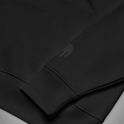 Eine Nahaufnahme des linken Ärmels eines schwarzen Regular Fit Hoodies der Marke FORCE ZERO im Black Stealth Design zeigt das präzise, rund gestickte FORCE ZERO Logo dezent Ton-in-Ton in Schwarz oberhalb des gerippten Ärmelbündchens.