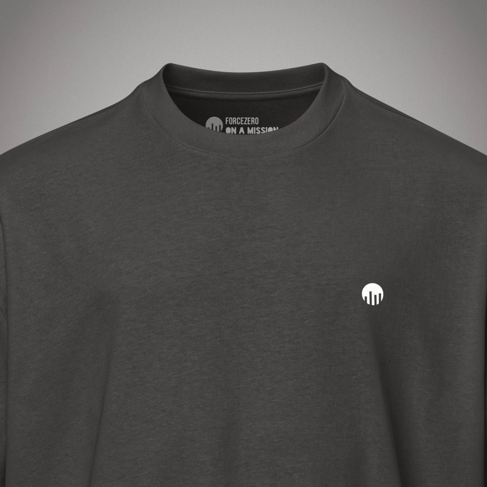 Eine Nahaufnahme Kragen eines schwarzen Boxy Cut T-Shirts der Marke FORCE ZERO zeigt den Nackeninnendruck mit dem Markennamen und dem weißen Slogan-Schriftzug „ON A MISSION“ unter einem Rundhalsausschnitt sowie einen kleinen, runden, weißen Logo-Print auf der linken Brust.