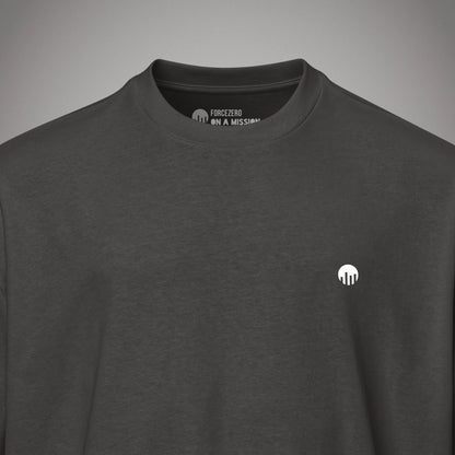 Eine Nahaufnahme Kragen eines schwarzen Boxy Cut T-Shirts der Marke FORCE ZERO zeigt den Nackeninnendruck mit dem Markennamen und dem weißen Slogan-Schriftzug „ON A MISSION“ unter einem Rundhalsausschnitt sowie einen kleinen, runden, weißen Logo-Print auf der linken Brust.