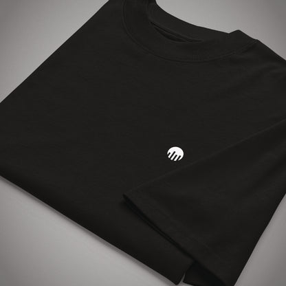 Nahaufnahme eines gefalteten schwarzen Oversized T-Shirts der Marke FORCE ZERO aus der Rogue Mode Design-Schiene mit Fokus auf den kleinen weißen Logo-Print auf der Brust