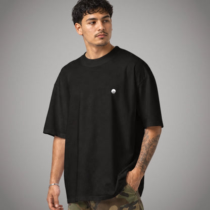 Ein schwarzes Oversized T-Shirt der Marke FORCE ZERO im Rogue Mode Raw Design am Model in einer halbseitig gedrehten Produkt-Vorderansicht mit einem kleinen, weißen Logo-Print auf der linken Brustseite.