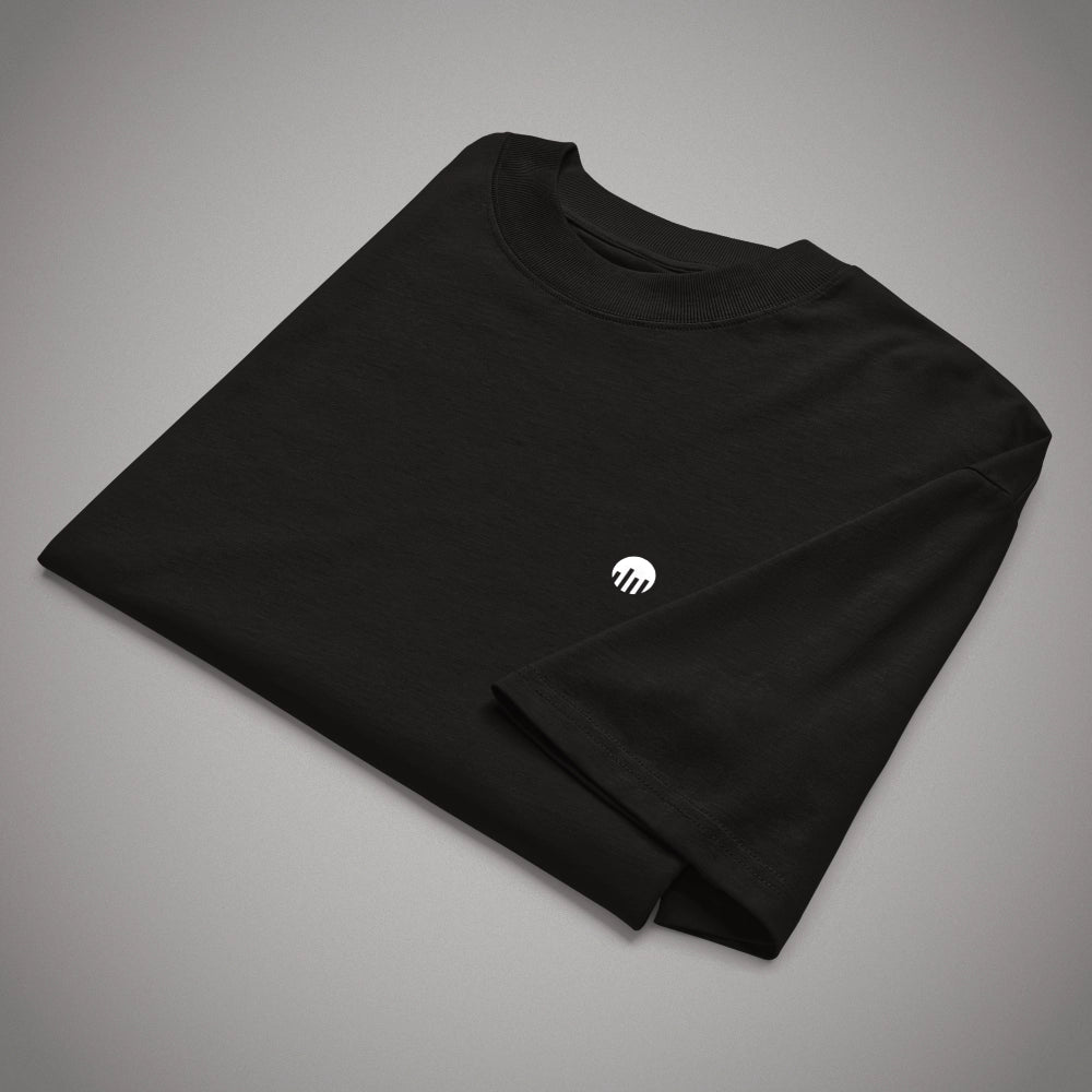Ein gefaltetes schwarzes Oversized T-Shirt der Marke FORCE ZERO im Rogue Mode Raw Design in der Produkt-Vorderansicht (Mockup) mit Fokus auf den kleinen, weißen, kreisförmigen Logo-Print auf der Brust.