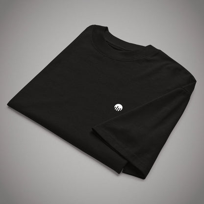 Ein gefaltetes schwarzes Oversized T-Shirt der Marke FORCE ZERO im Rogue Mode Raw Design in der Produkt-Vorderansicht (Mockup) mit Fokus auf den kleinen, weißen, kreisförmigen Logo-Print auf der Brust.