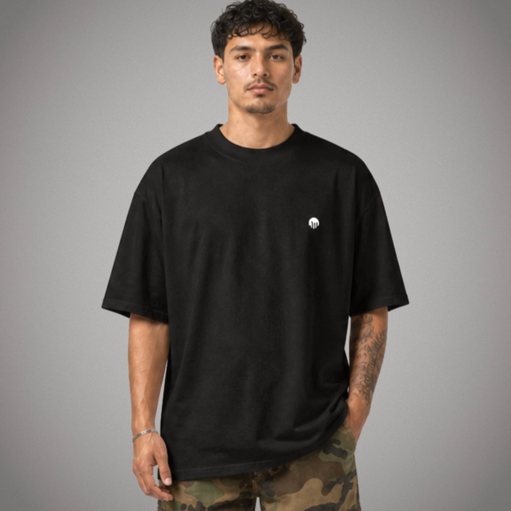 Ein schwarzes Oversized T-Shirt der Marke FORCE ZERO im Rogue Mode Raw Design am Model in der Produkt-Vorderansicht mit einem minimalistischen, kleinen weißen Logo-Print auf der linken Brustseite.