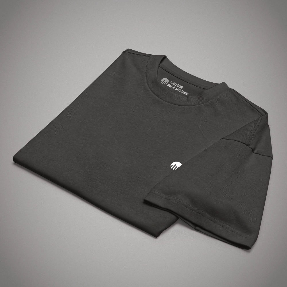 Ein schwarzes Boxy Cut T-Shirt der Marke FORCE ZERO im Rogue Mode Renegade Design zeigt als Produkt-Vorderansicht (Mockup) eine angewinkelte Ansicht des flach zusammengelegten Kleidungsstücks mit gut sichtbarem Nackeninnendruck „ON A MISSION“ und dem kleinen, weißen Logo-Print auf der linken Brust.